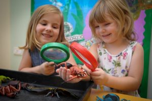 Two children plating with magnifying glasses